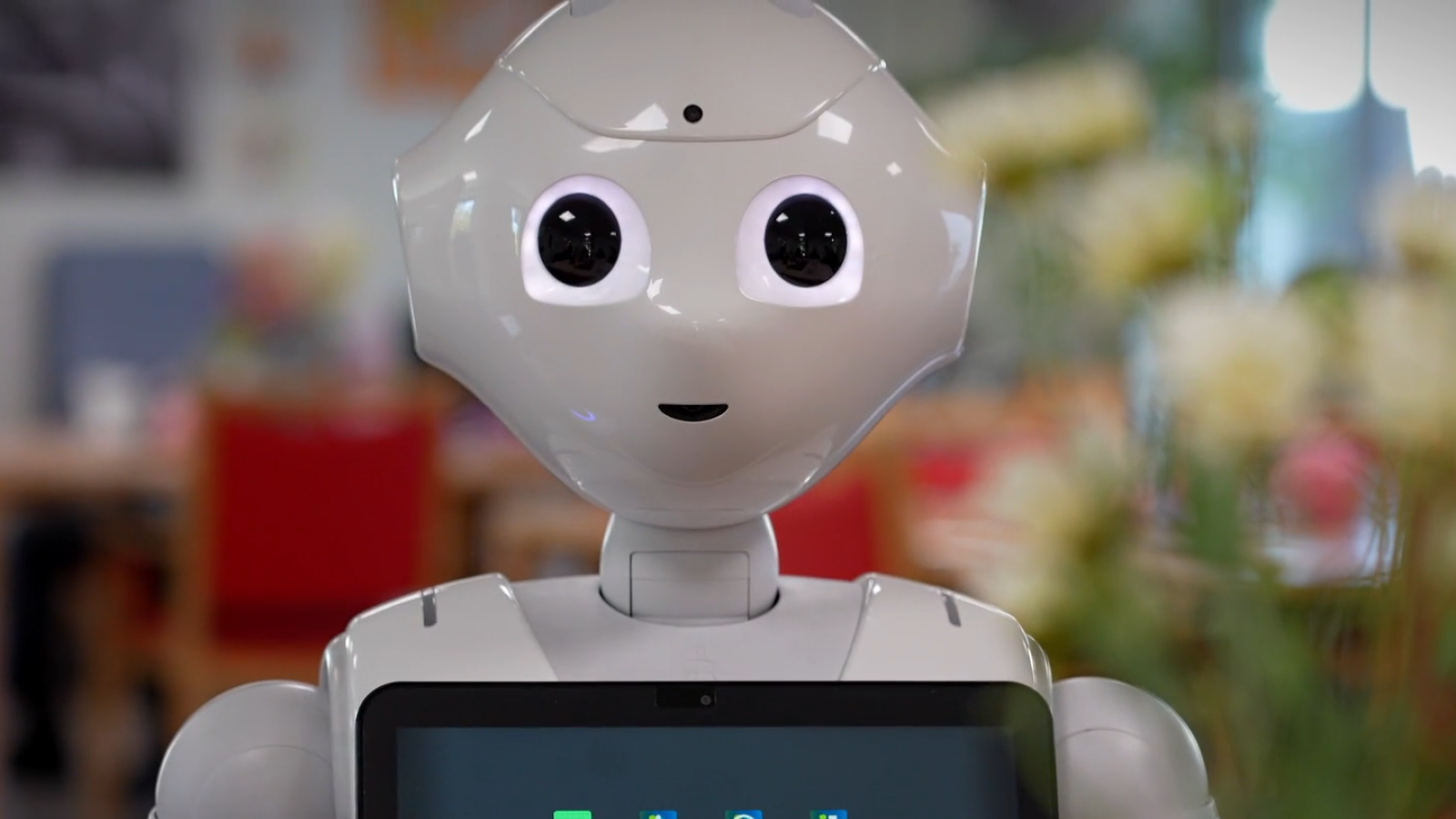 Humanoider weißer Roboter mit Tablet auf der Brust schaut nach vorne